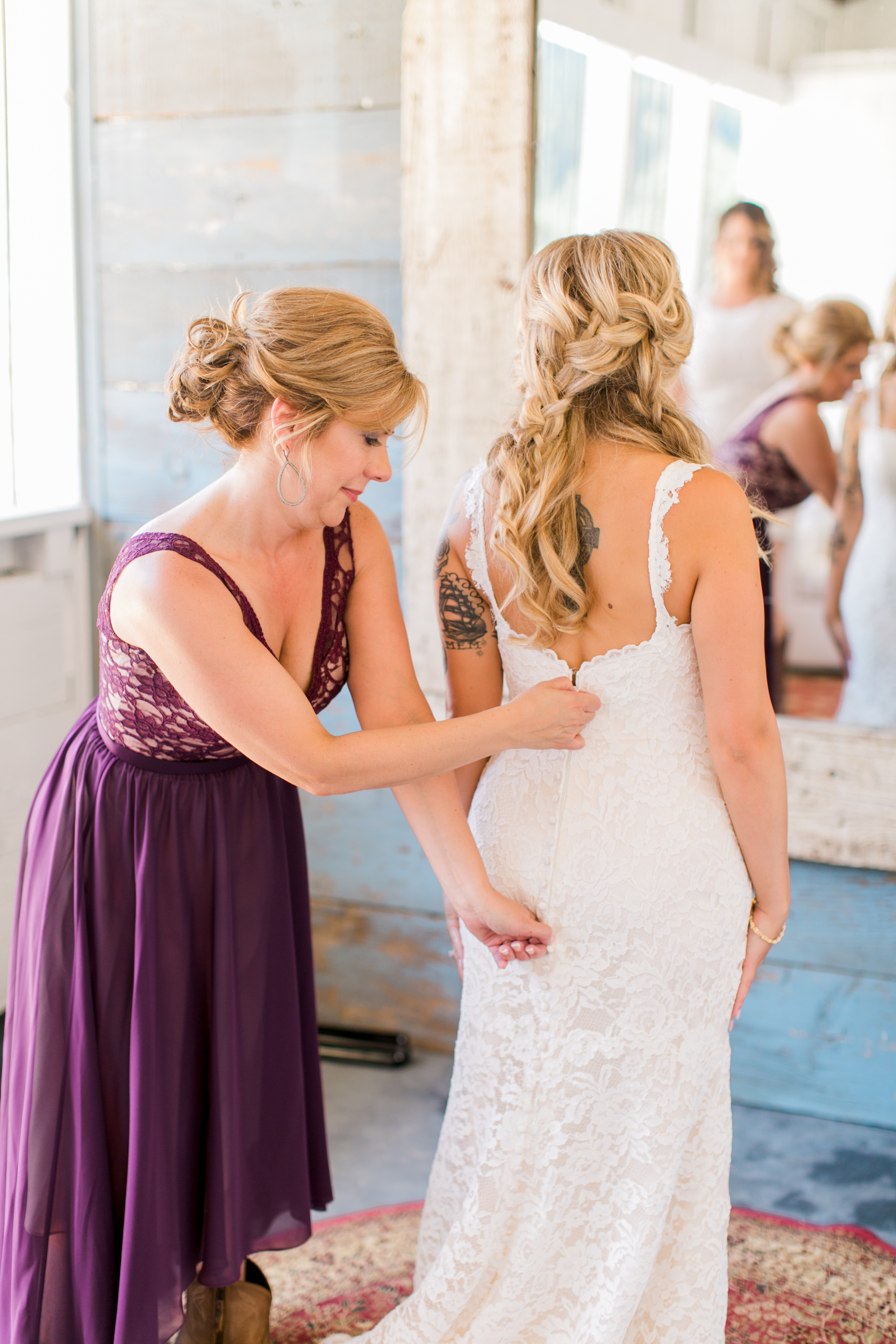 Mom helping bride zip up wedding dress